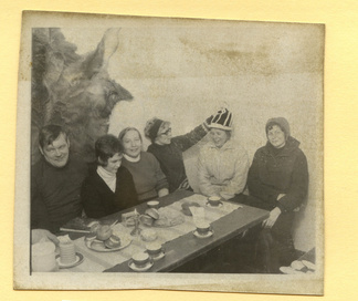 Kulomäen majan hiihtäjiä. Ajankohtana lie ollut Laskiainen, koska pöydällä on laskiaispullia. Huomatkaa hirventalja majan seinällä.