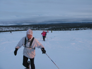 Laskevan auringon säteet punaavat lumikenkäilijöitä.